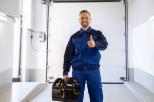repairman giving a thumbs up. He is holding a large tool box and is standing in front of a garage door