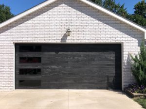 a wood-toned garage door with vertically stacked windows on residential home